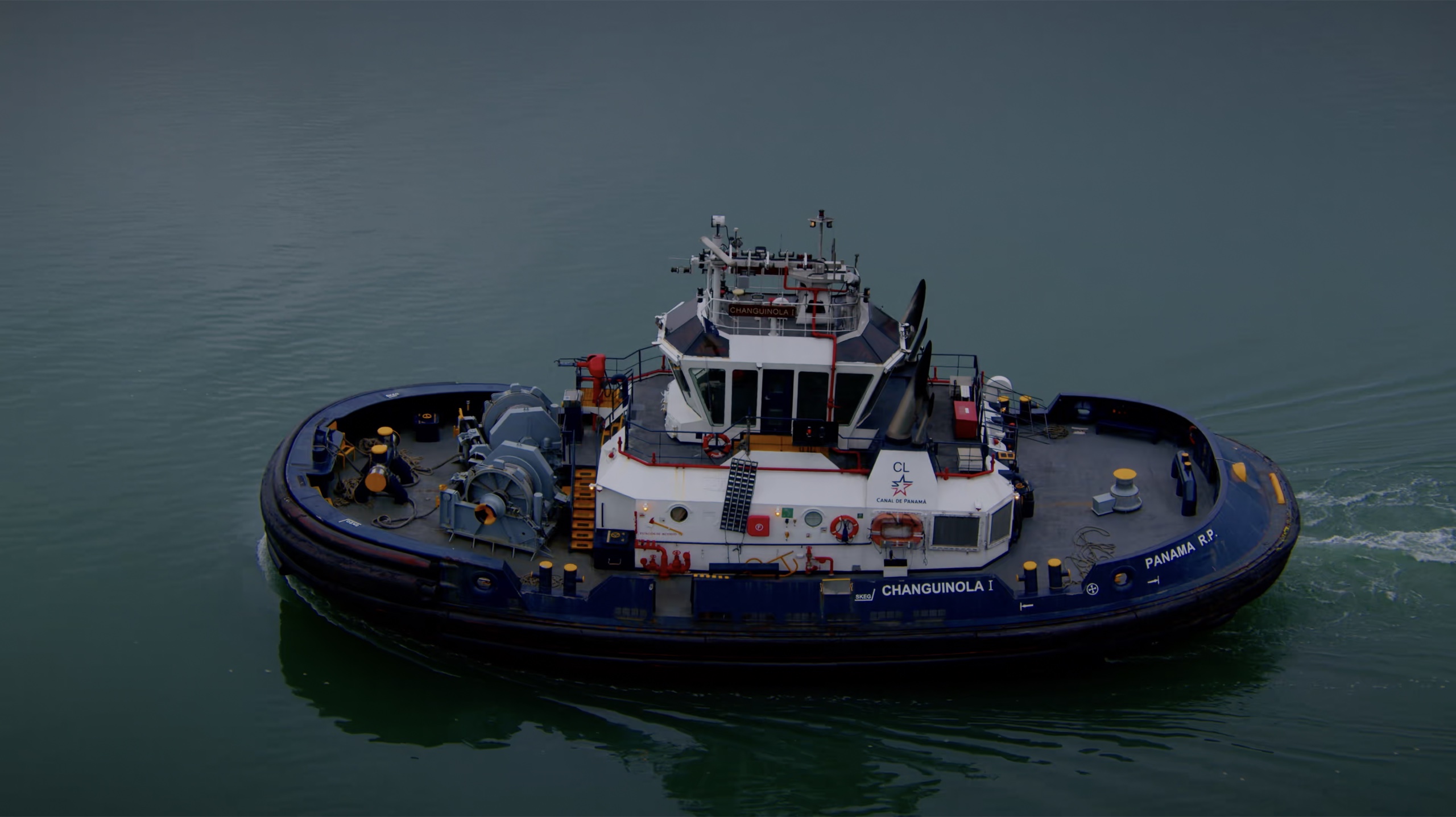 A Panama Canal tugboat moving across blue water.