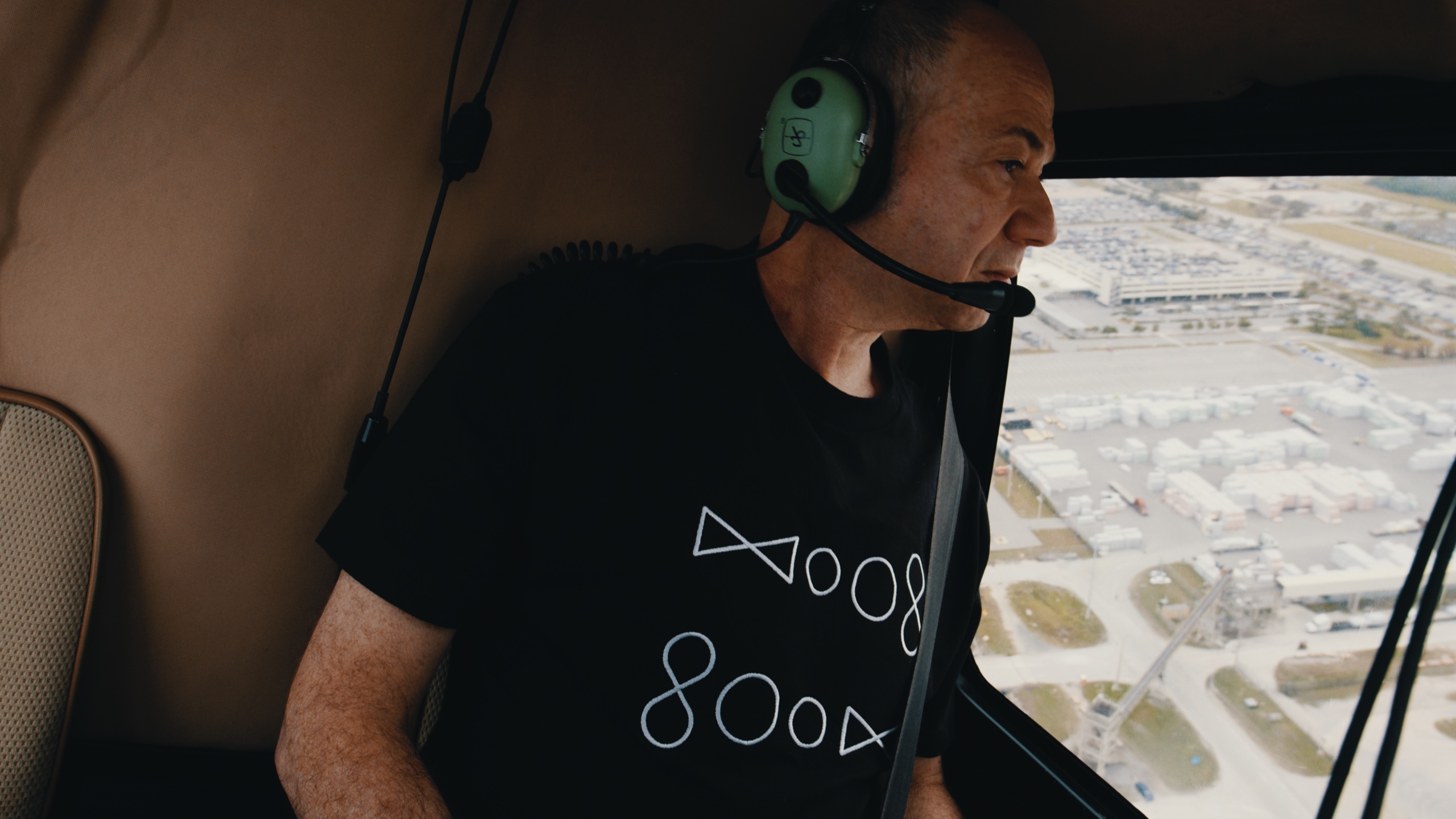 A man wearing an aviation headset inside a helicopter.